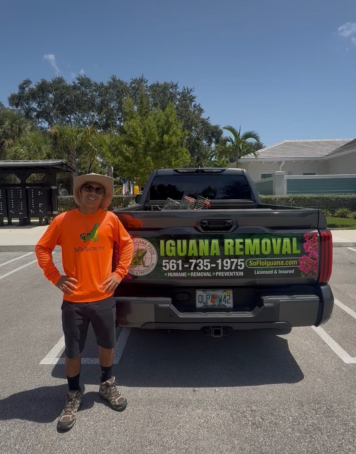 Iguana removal technician in sun hat by truck